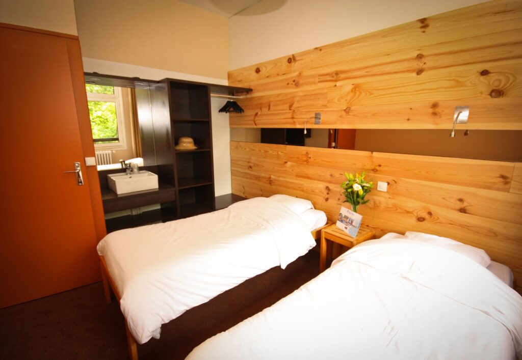 Chambre double avec deux lit séparés et une vasque devant un miroir