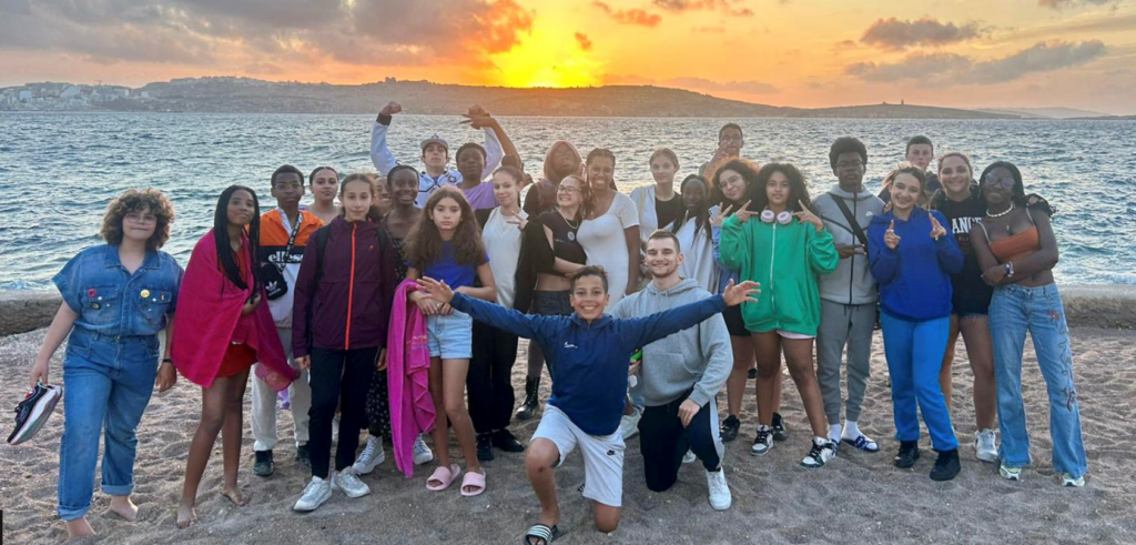 groupe de colons sur la plage devant un coucher de soleil